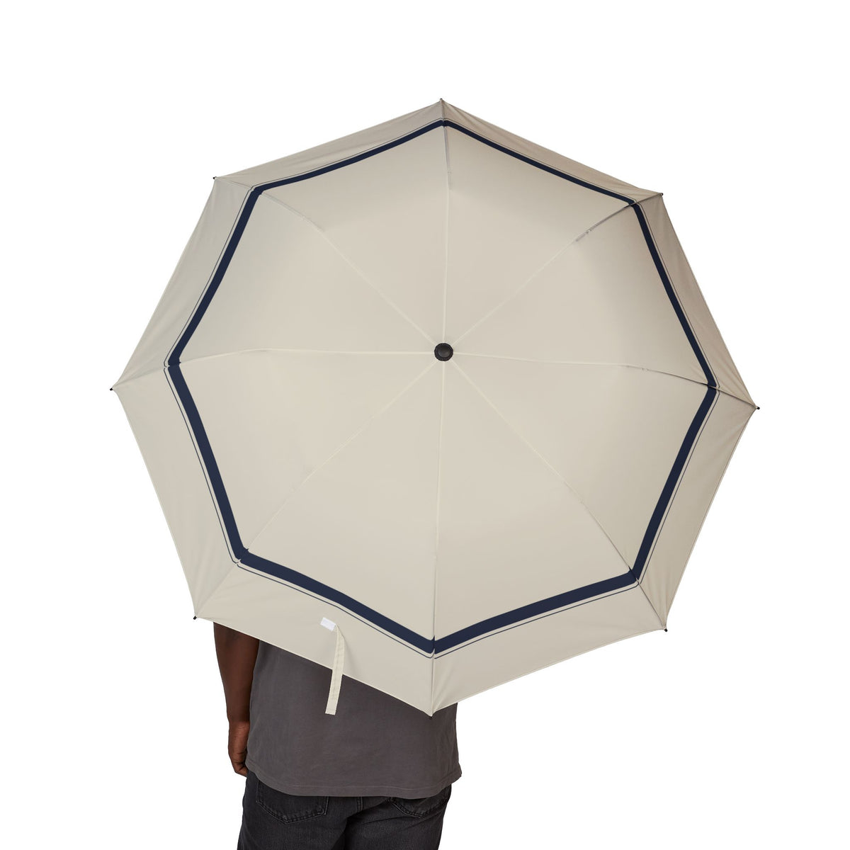 Person holding the Mowbray ivory navy-border folding umbrella, canopy from above