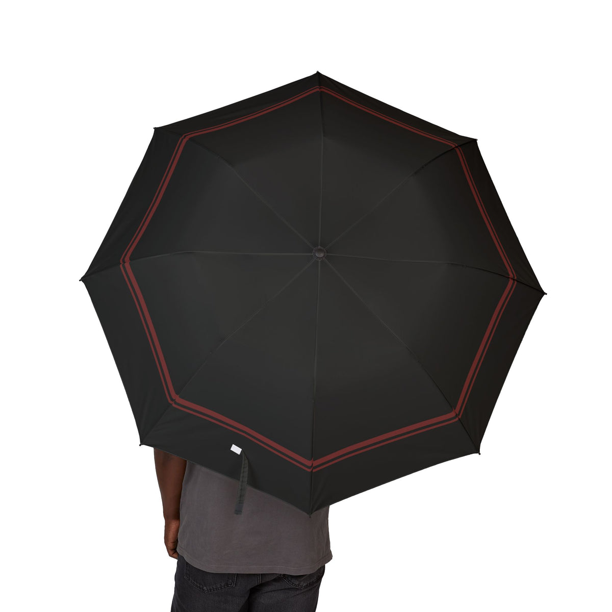 Person holding the Capet black oxblood-border folding umbrella, canopy from above