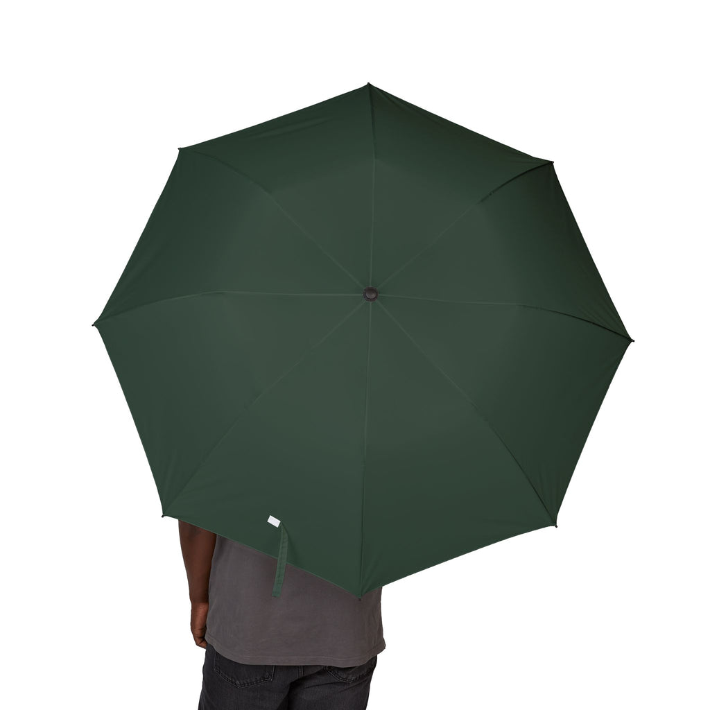 Person holding The Talbot bottle green folding umbrella, canopy from above
