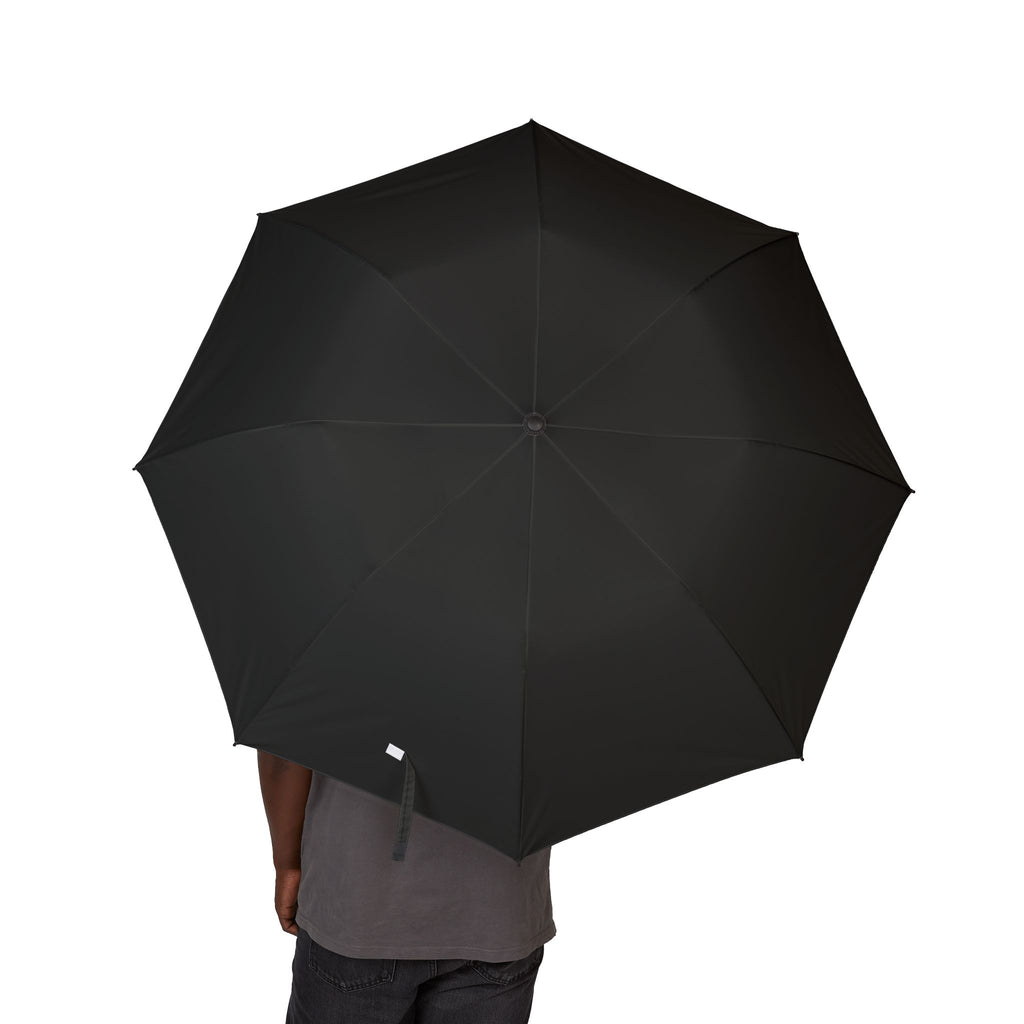 Person holding The Montmorency ink black folding umbrella, canopy from above
