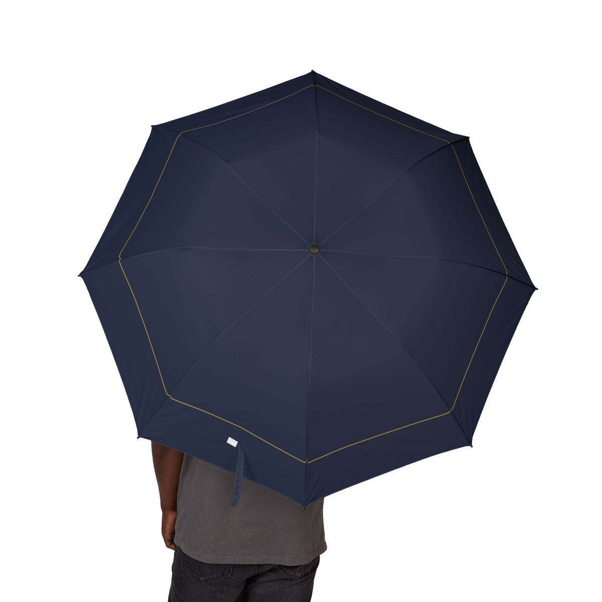 Person holding the Valois navy gold-hem folding umbrella, canopy from above